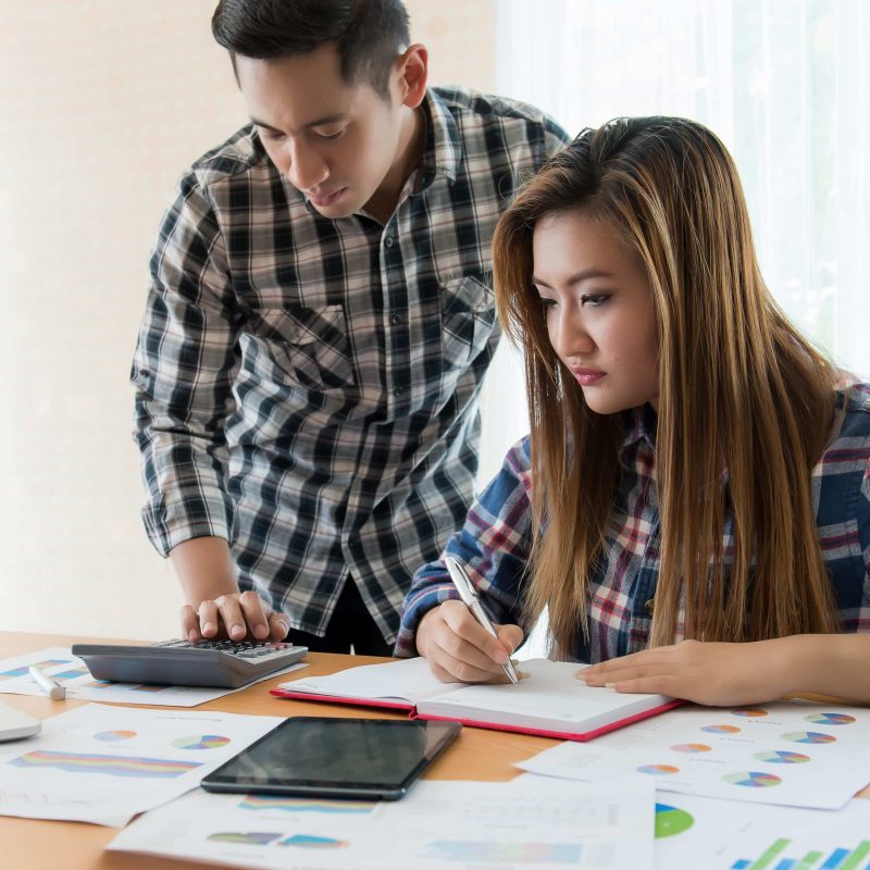 Businesswoman in casual plaid shirt writing with businessman using calculator for tax form completion,Internal revenue service inspector checking financial document,Planning budget,Freelance,Audit.